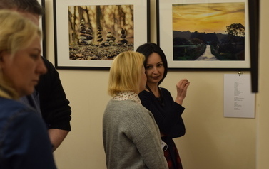 Dwie kobiety rozmawiają ze sobą. na ścianie w tle widać fotografie przyrody.