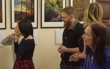 Grupa ludzi ogląda fotografie w Galerii