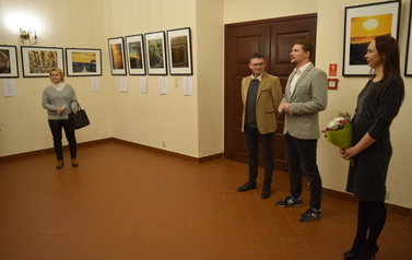 dwoje mężczyzn oraz dwie kobiety. jeden z nich opowiada o wystawie. kobieta trzyma bukiet kwiat&oacute;w.