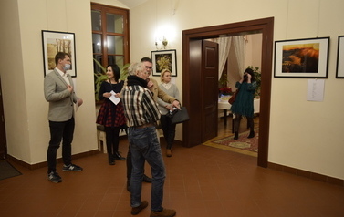 Grupa ludzi podczas wernisażu fotografii i poezji.