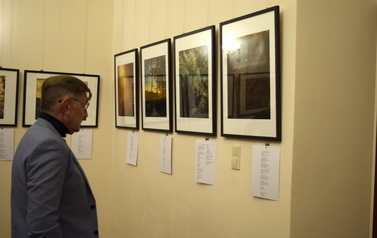 Elegancki mężczyzna ogląda fotografie wiszące na ścianie w galerii.