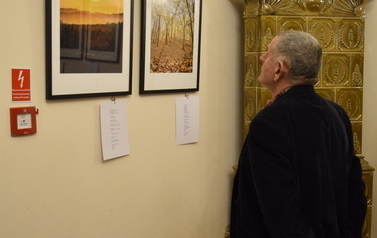 Starszy mężczyzna ogląda fotografie w galerii.