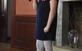 Mała dziewczynka w granatowej sukience recytuje wiersz