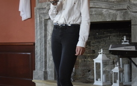 Dziewczyna w galowym stroju recytuje wiersz przed kominkiem