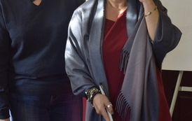 Dwie kobiety rozmawiają. Jedna ma białą laskę w ręce i gogle na oczach.